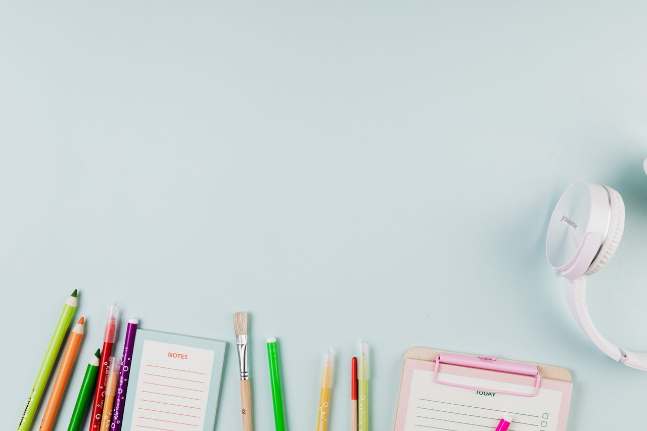 about-06 Flat lay of colorful stationery and white headphones on a blue background, ideal for creative projects.