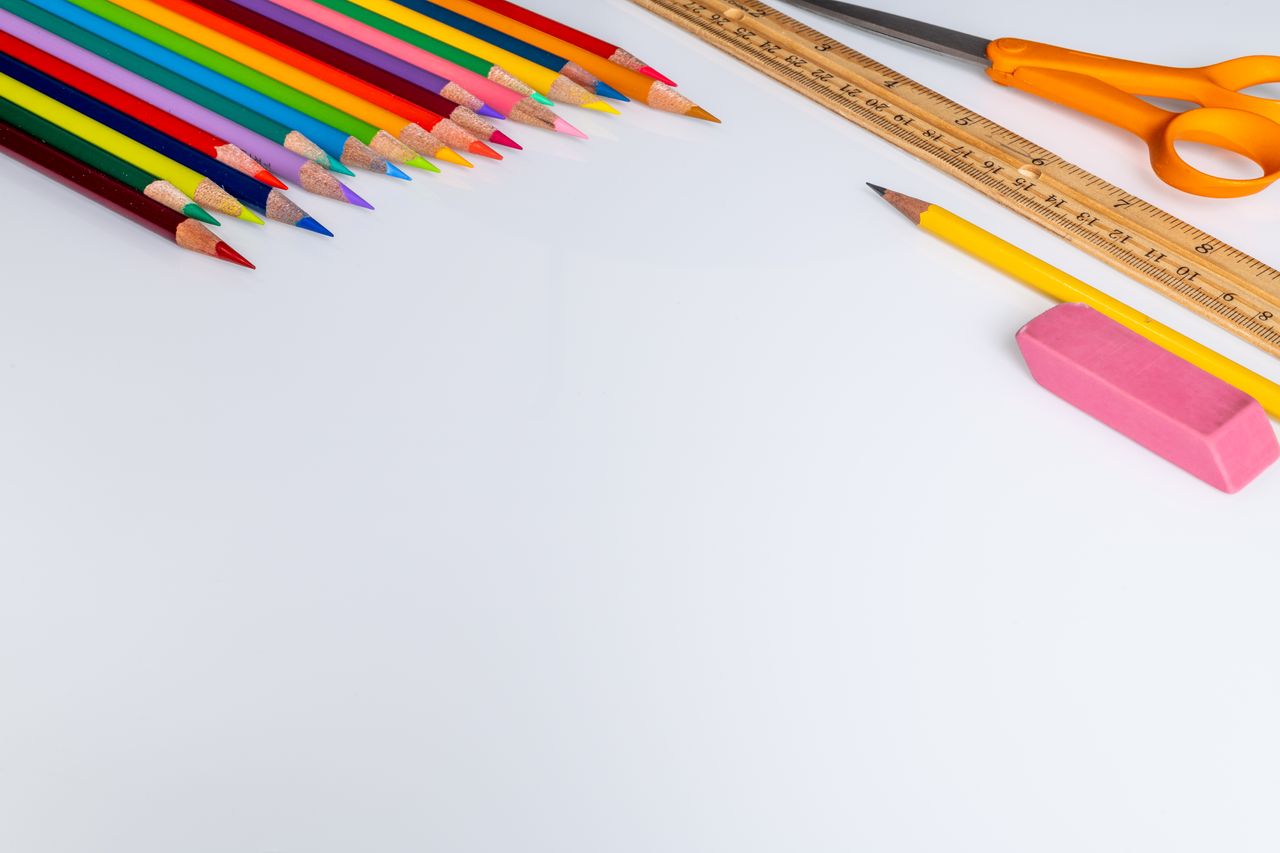 about-02 Set of colored pencils for drawing placed on white surface near wooden ruler and scissors near eraser in light studio