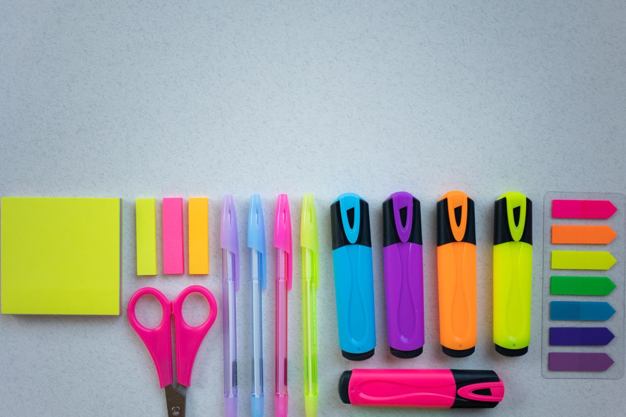 about-05 Flat lay of colorful school supplies including pens and highlighters on a white surface.