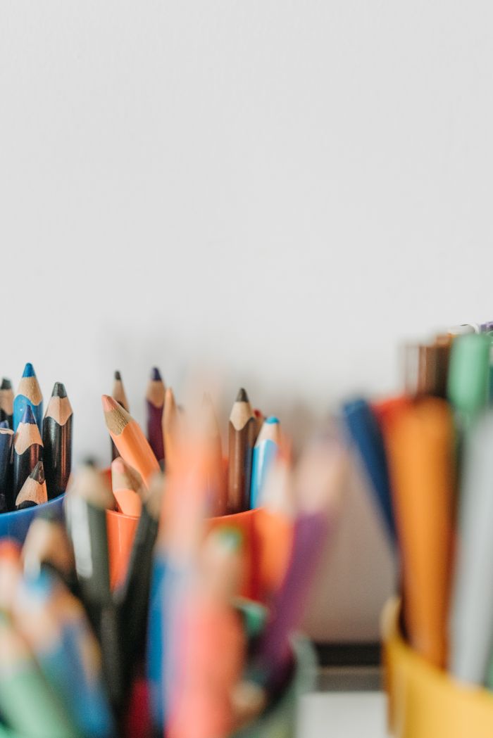 about-04 Close-up view of colored pencils in holders on a blurred background.